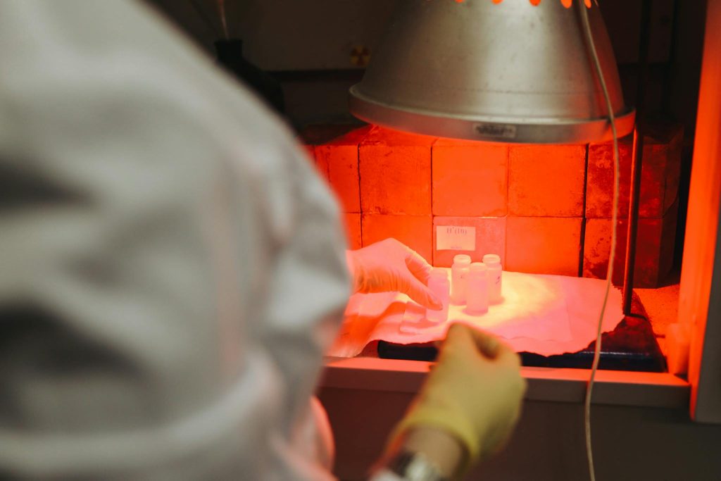 A scientist carefully handles samples in a lab under infrared light, reflecting precision and safety.